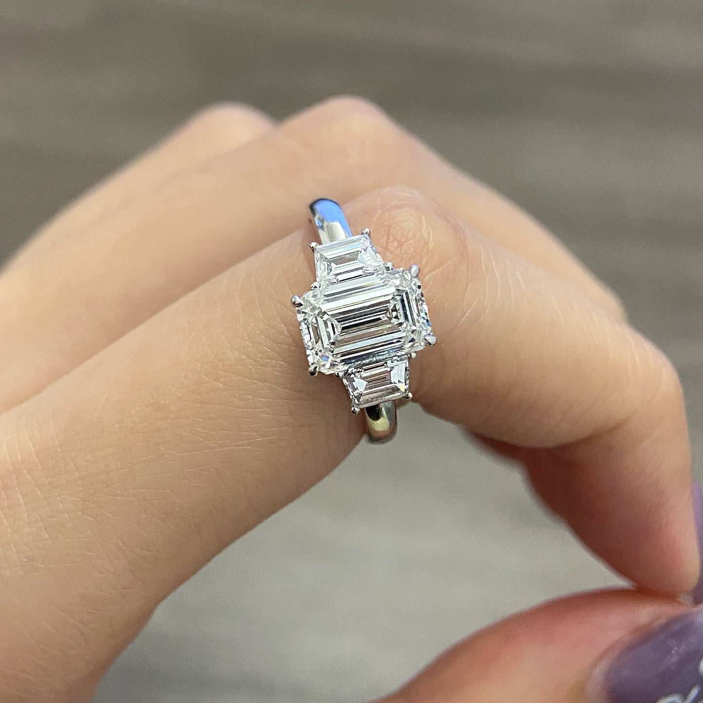 Emerald cut CVD diamond three stone engagement ring with side stones