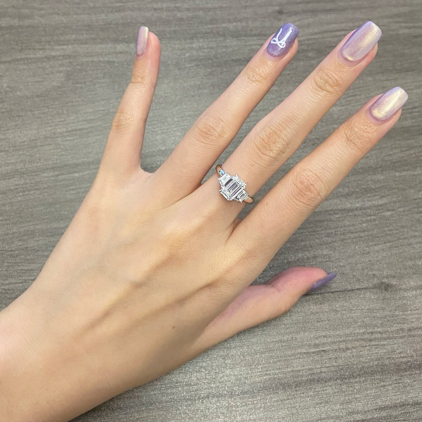 Emerald cut CVD diamond three stone engagement ring with side stones