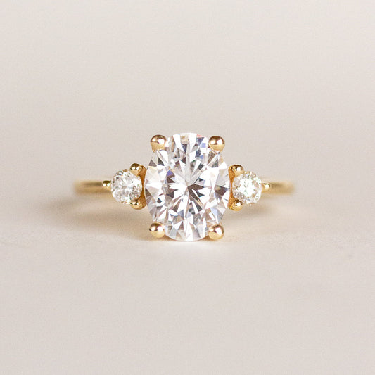 Oval cut CVD lab grown diamond three stone engagement ring with tapered side stones in a sleek, polished band setting