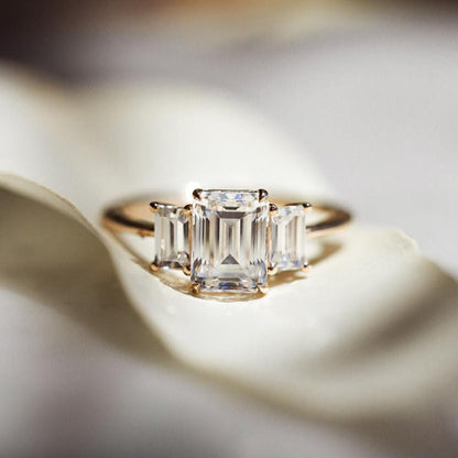 Three stone engagement ring with emerald cut moissanite center