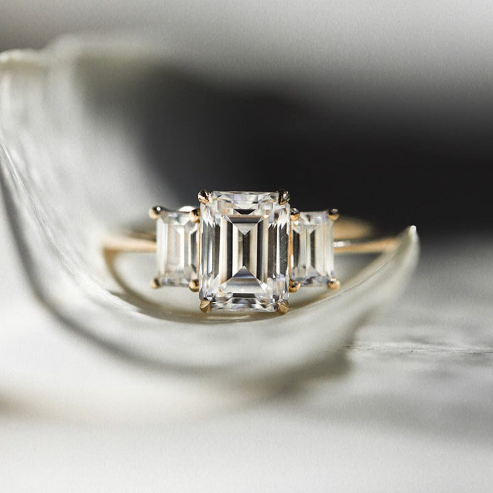 Three stone engagement ring with emerald cut moissanite center