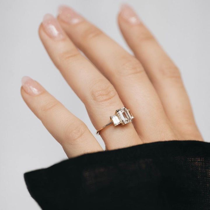 Three stone engagement ring with emerald cut moissanite center