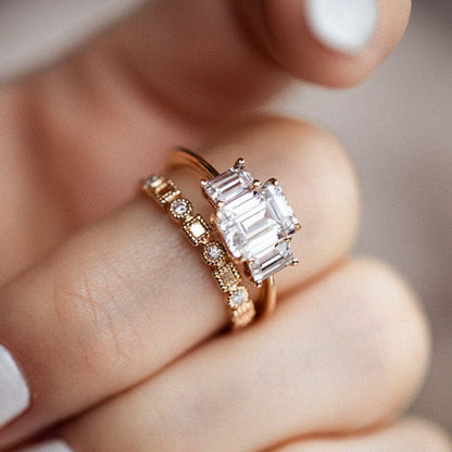 Three stone engagement ring with emerald cut moissanite center