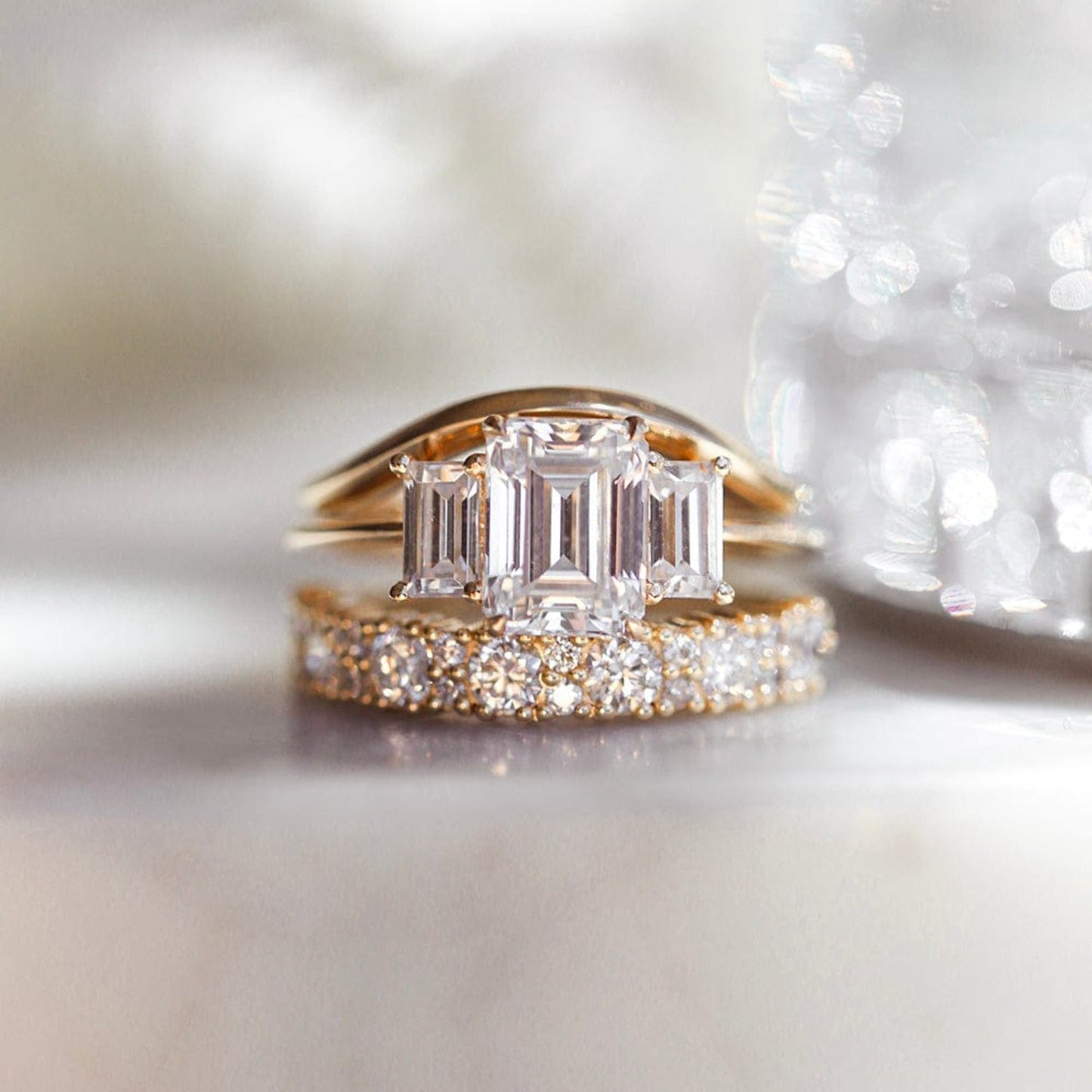 Three stone engagement ring with emerald cut moissanite center