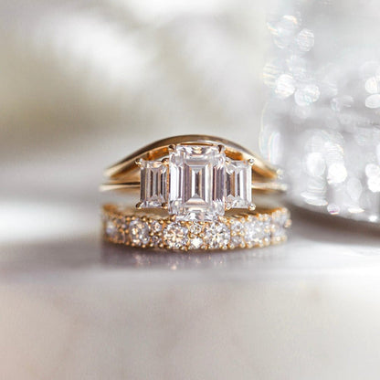 Three stone engagement ring with emerald cut moissanite center
