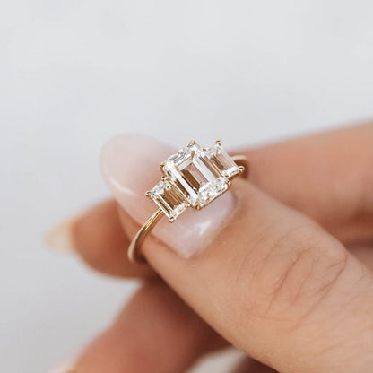 Three stone engagement ring with emerald cut moissanite center